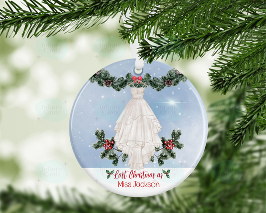 Christmas ornament with a dress design and festive elements, hanging on a tree.
