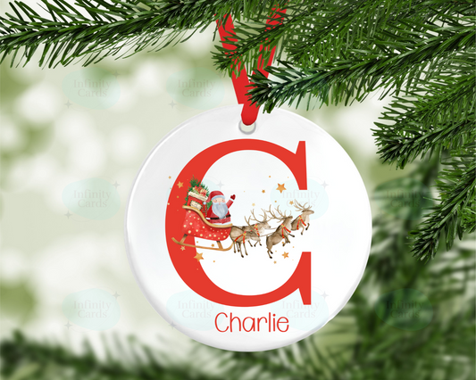 Christmas ornament with letter 'C' and Santa Claus design, hanging on a tree branch.