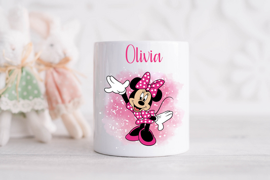 A glossy white ceramic money box with a personalised name 'Olivia' and the Minnie Mouse character design, featuring pink and black colors with glitter accents.
