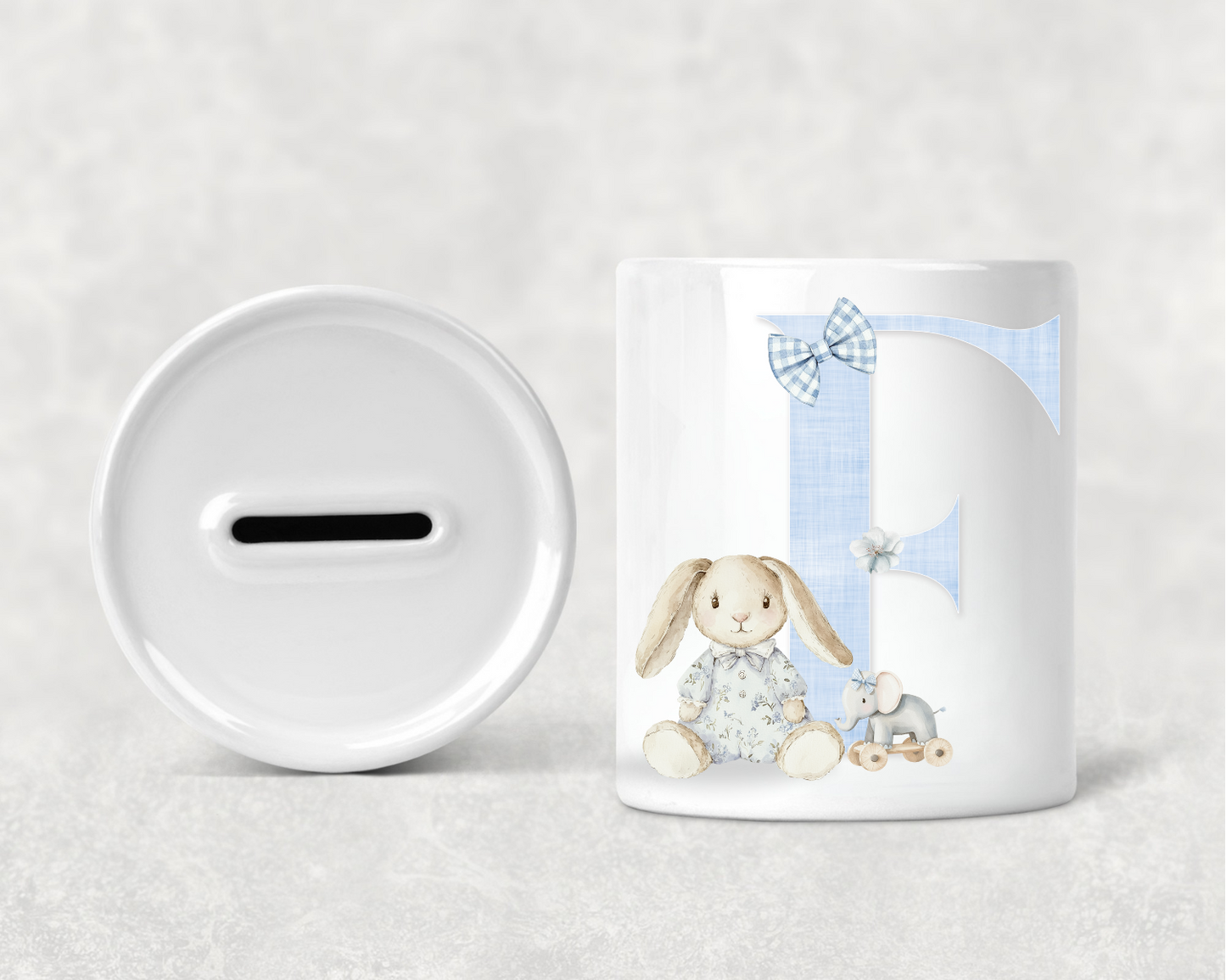 White mug with a rabbit design and a white piggy bank on a light gray background