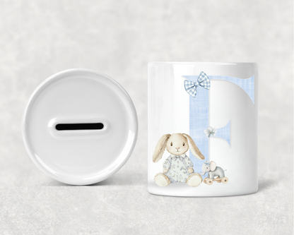 White mug with a rabbit design and a white piggy bank on a light gray background